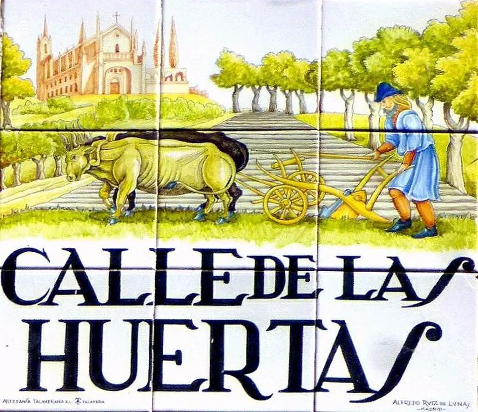 A ceramic street-name tile reading Calle de las Huertas, with a painted scene of a ploughman with two oxen and a church